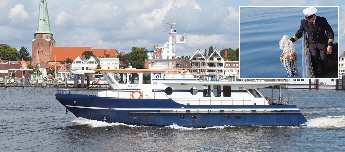 Ein blau-weißes Schiff sticht in See. Ruhiger Seegang. Auf einem weiteren kleinen Bild sieht man einen Kapitän, der eine Urne in das Wasser senkt